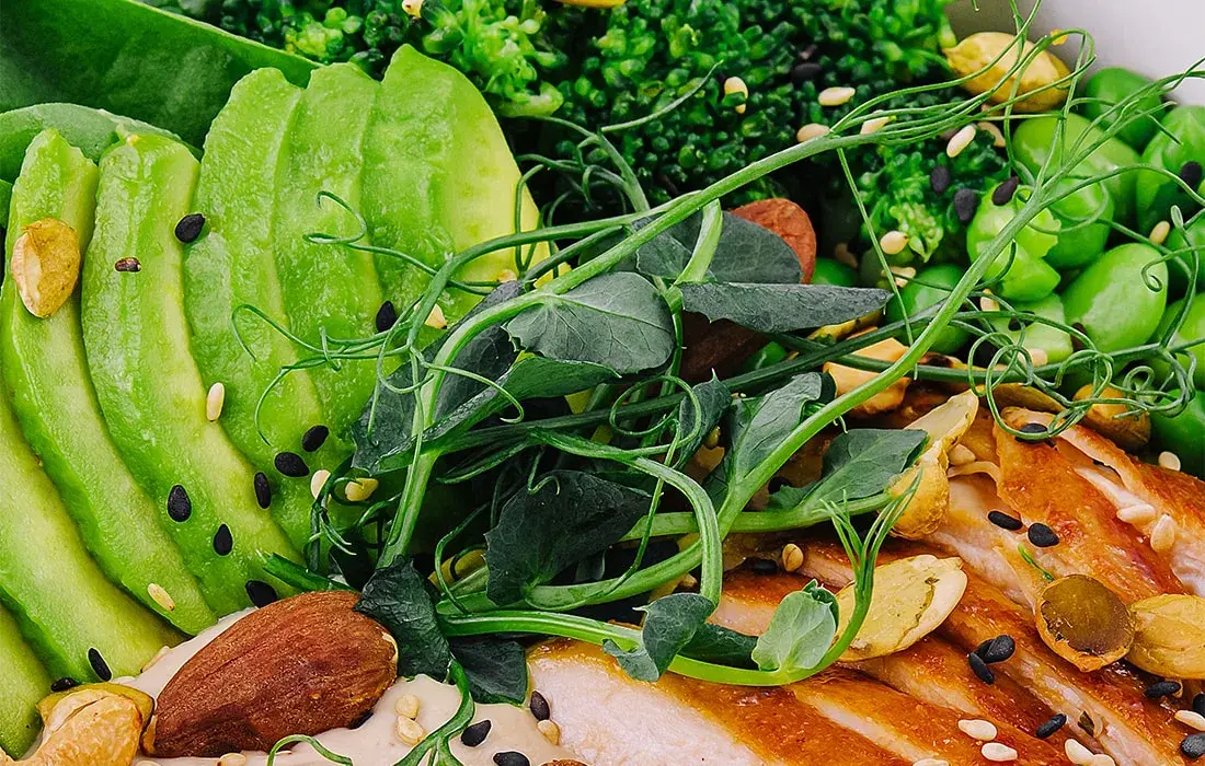 Plato saludable con aguacate, frutos secos, verduras verdes y proteína a la plancha, ideal para alimentación alcalina.